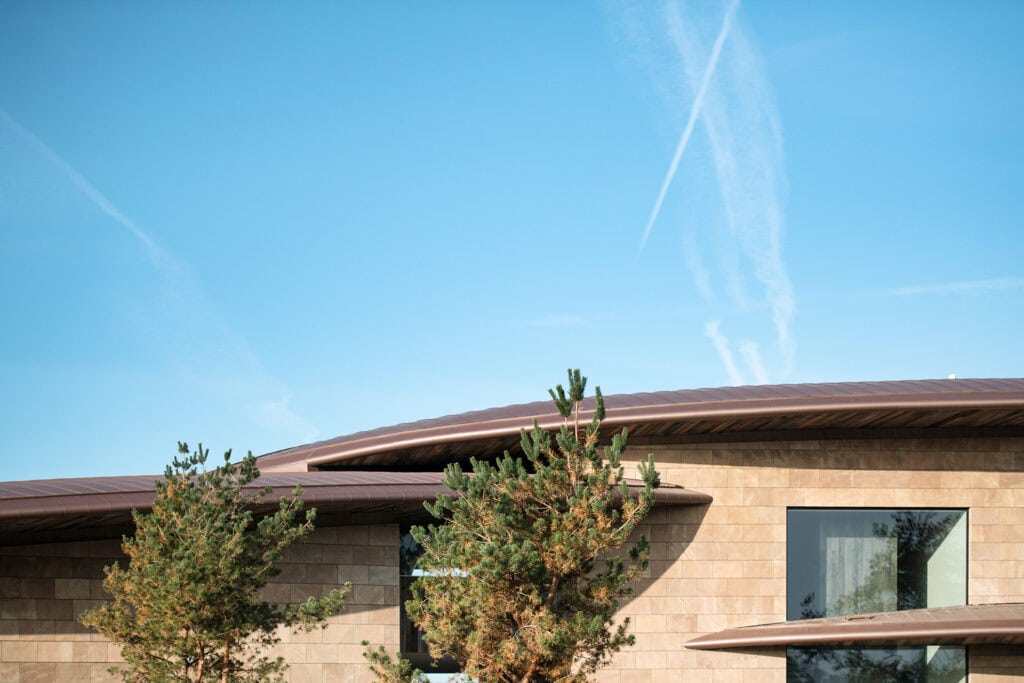 Moderne architectuur met natuurlijke elementen, dynamisch dakdesign en grote ramen voor lichtinval bij Studio REDD. Perfect voor duurzaam bouwen en hedendaagse woningbouw.