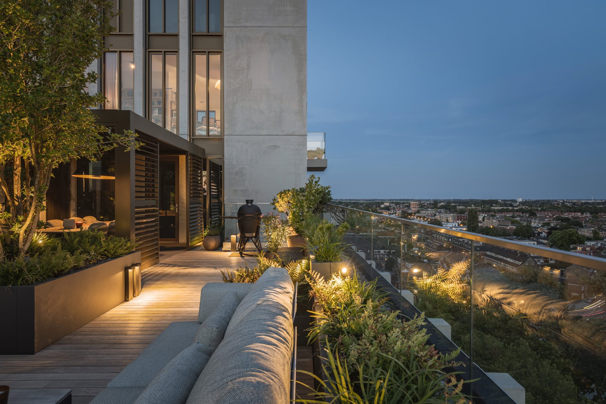 Moderne dakterras met uitzicht over de stad, voorzien van comfortabele zitplaatsen en groene planten, perfect voor ontspanning en genieten van de skyline.