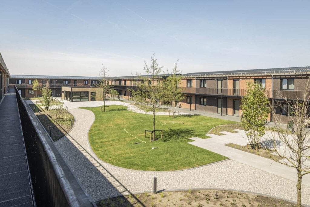 Uitzicht op de groene binnenplaats van Studio REDD met wandelpaden en jonge bomen, ideaal voor ontspanning en recreatie.