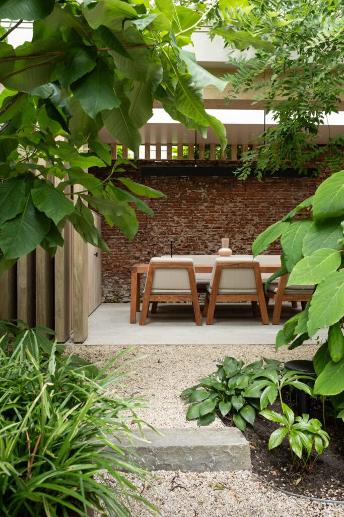 Gezellige tuin met houten tafel en groene planten bij Studio REDD, perfect voor ontspanning en buitenleven.